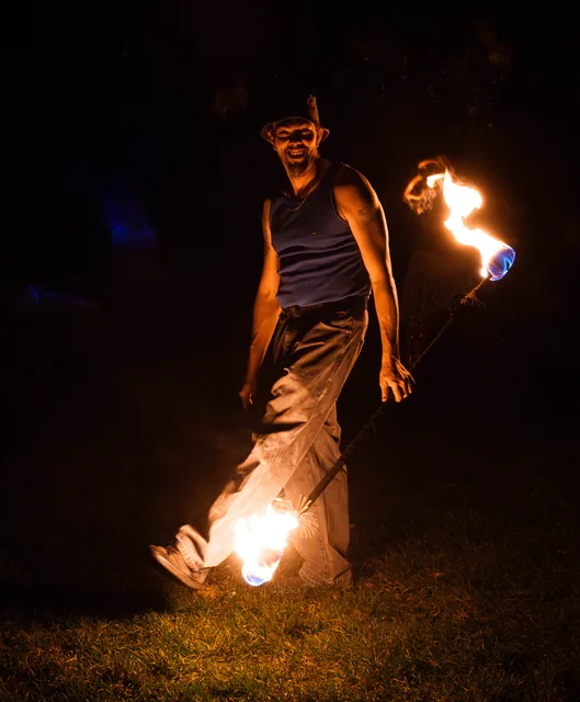 A fire performer smiling in the dark