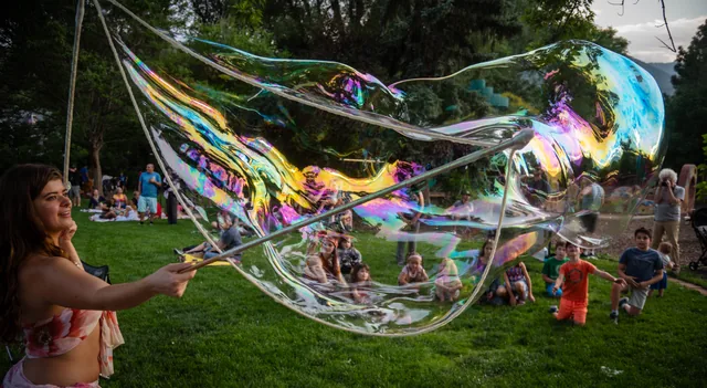An iridescent bubble and children in pursuit