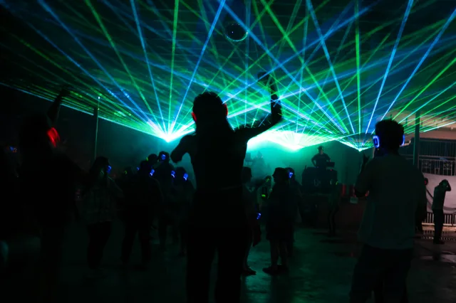 Dancers silhouetted beneath crossing lasers