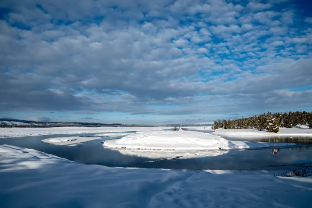 Snow, blue water, and patterned clouds