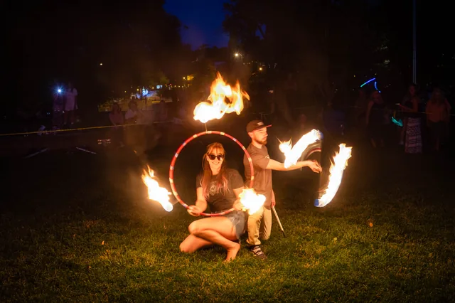 Two performers framed by fire at twilight